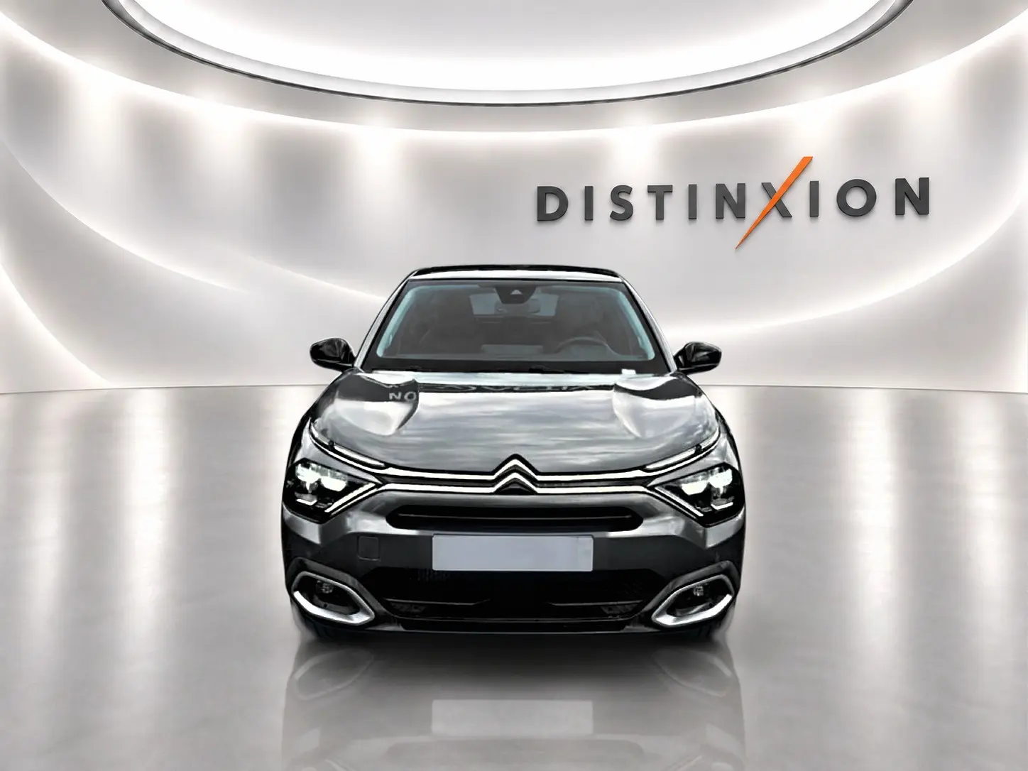 Citroën C4 gris vue de face dans un studio lumineux avec logo Distinxion en arrière-plan.