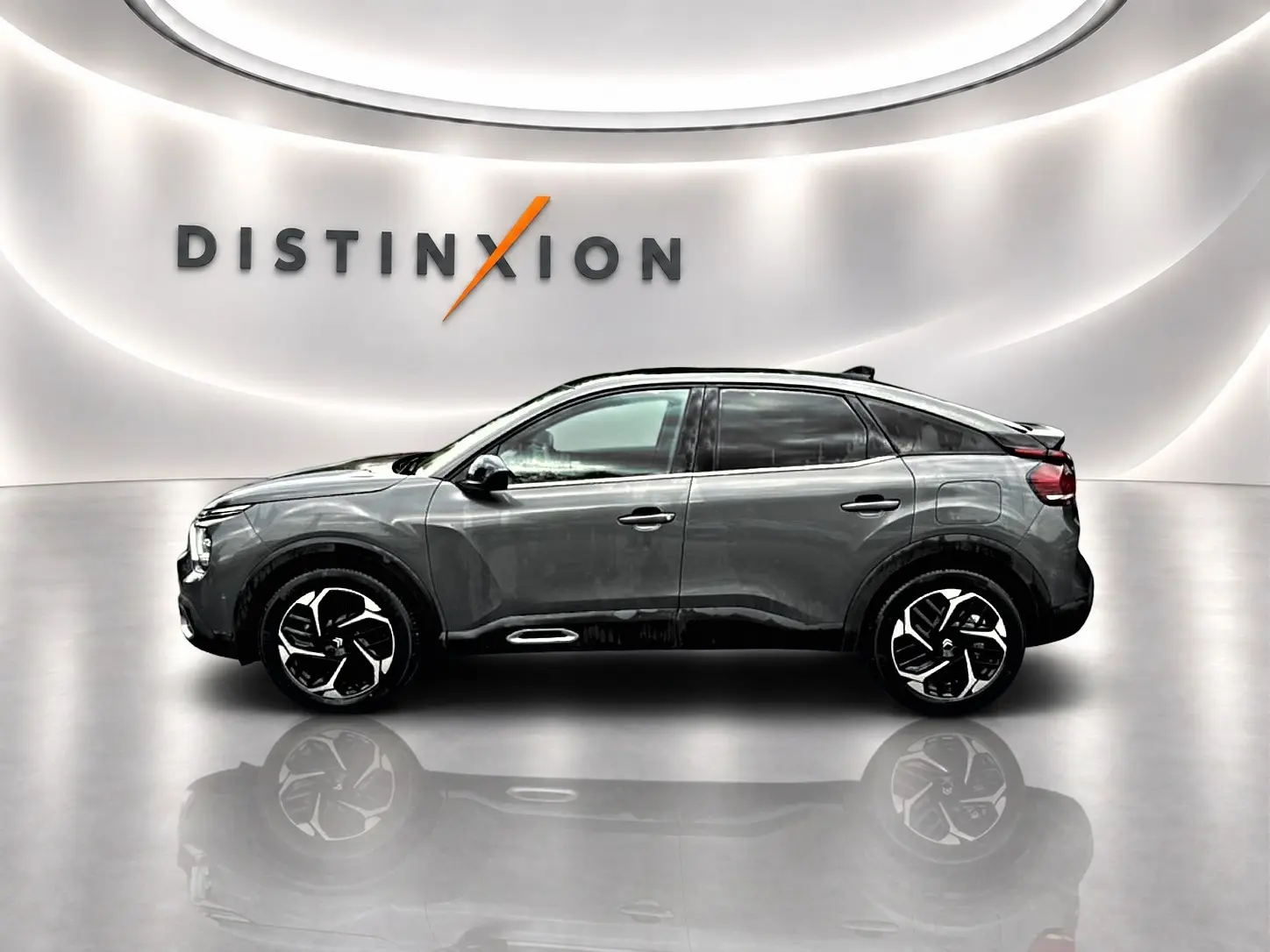 Profil droit d'une Citroën C4 gris métallisé 2024 avec jantes alliage, dans un showroom lumineux au logo Distinxion.