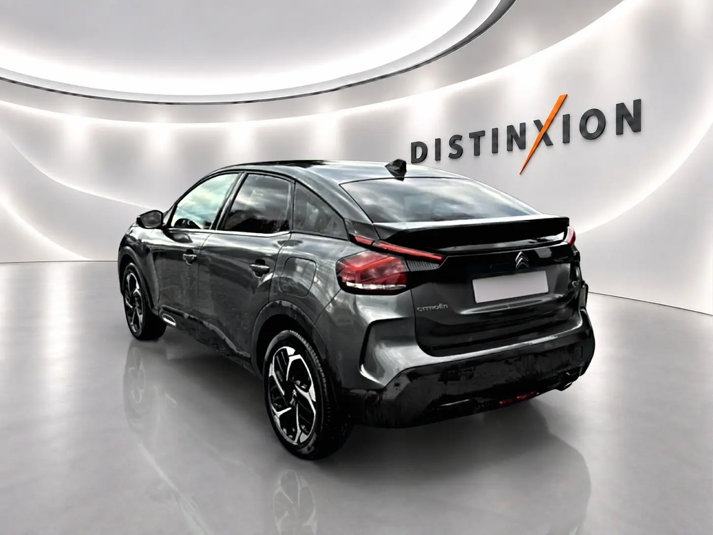Vue 3/4 arrière droite d'une Citroën C4 gris métallisé avec jantes alliage dans un showroom lumineux.