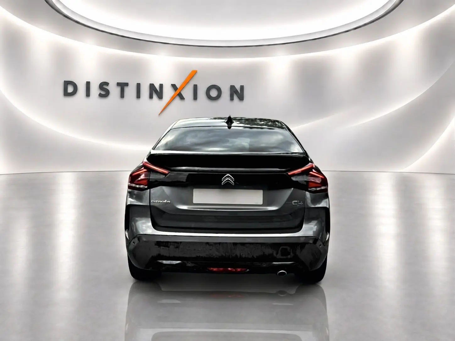 Vue arrière d'une Citroën C4 gris métallisé 2024, avec feux LED et logo distinctif sur fond blanc lumineux.