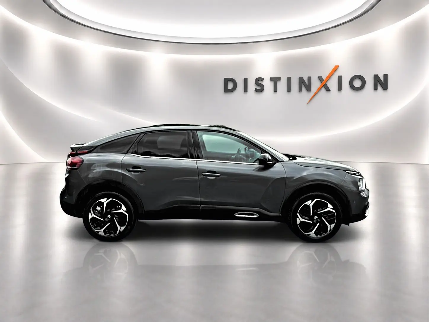 Profil droit d'une Citroën C4 gris métallisé 2024 avec jantes alliage et vitres teintées, sur fond lumineux blanc.