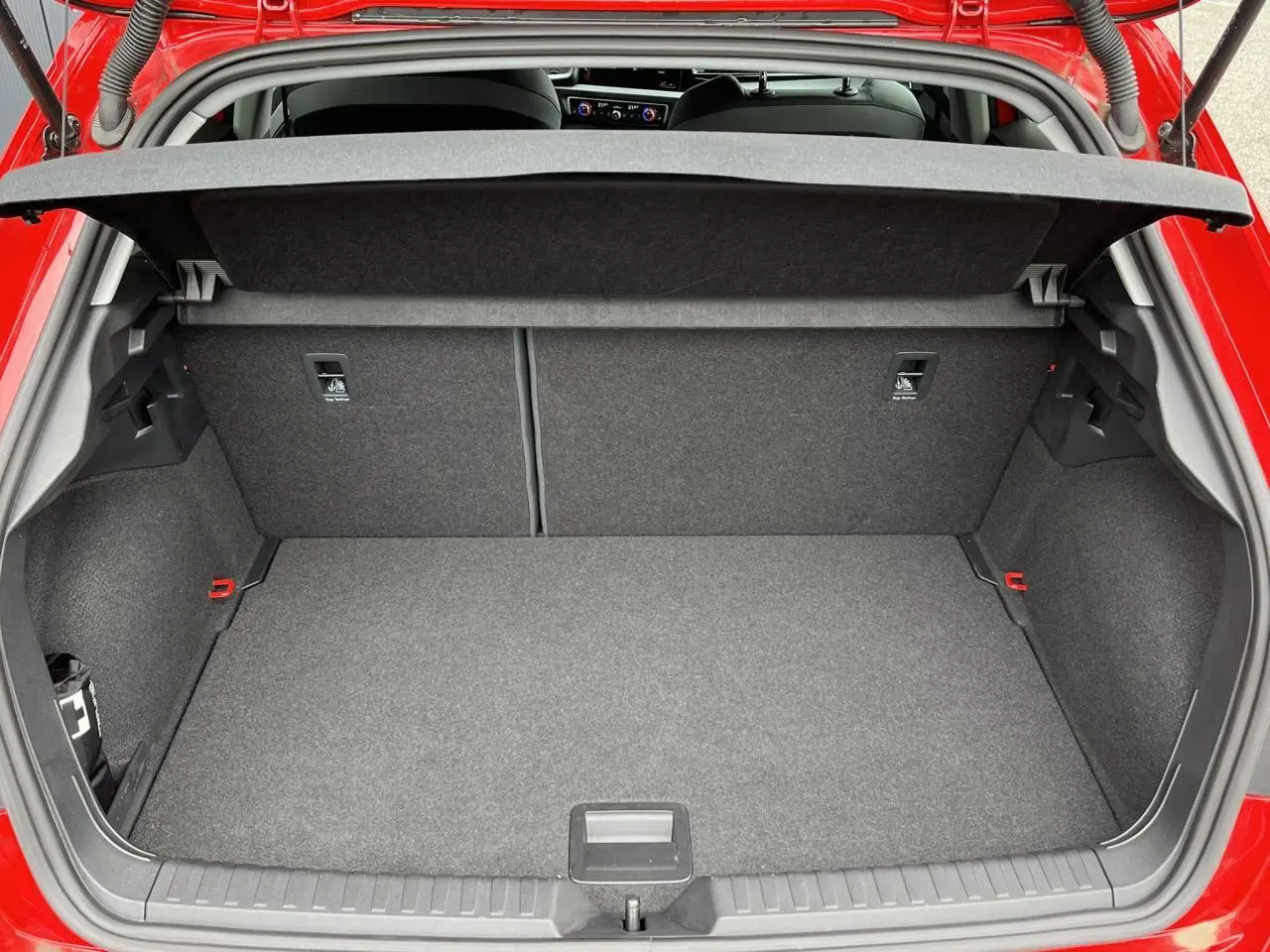Coffre ouvert vu de l'arrière d'une Audi A1 Sportback rouge Misano, intérieur gris et banquette rabattable.