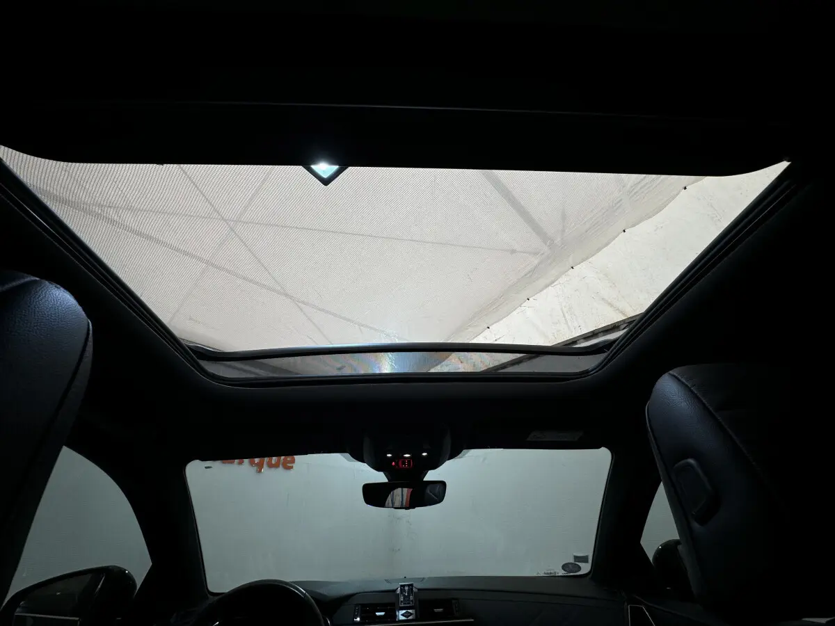 Vue intérieure du toit ouvrant panoramique et tableau de bord du DS7 Crossback E-TENSE 4x4 Grand Chic, sièges cuir noirs visibles.