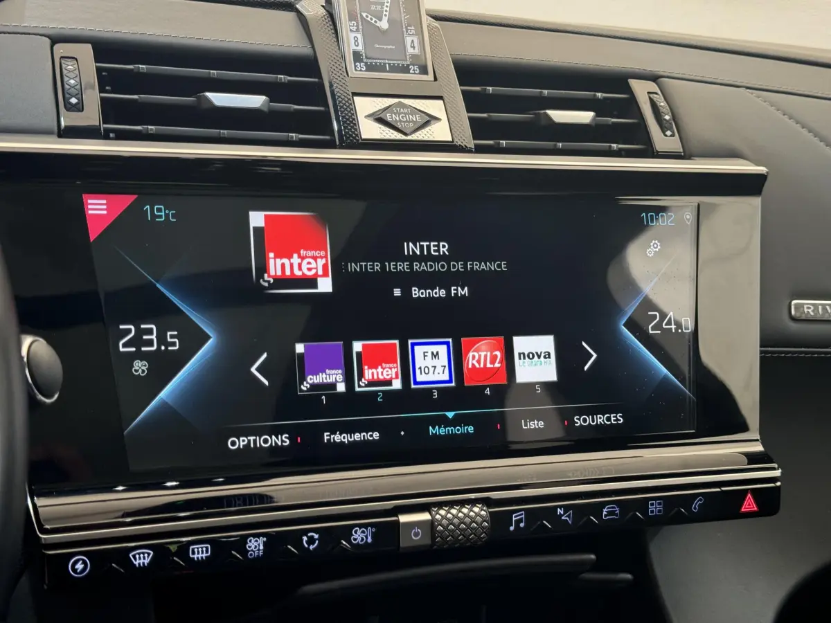 Vue rapprochée de l’écran tactile central du tableau de bord du DS7 Crossback bleu, affichant la radio FM et la climatisation digitale.