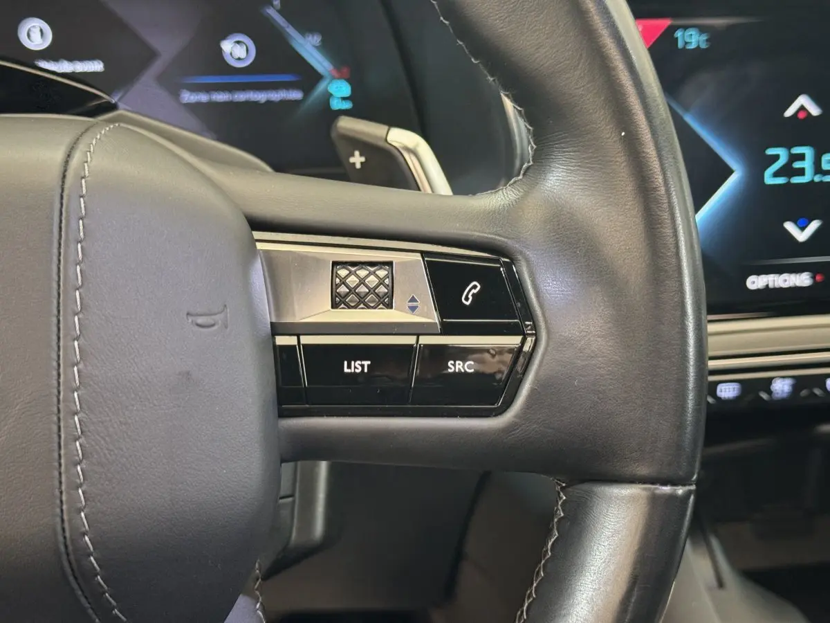 Gros plan sur le volant cuir noir du DS7 Crossback E-TENSE 4x4 Grand Chic avec commandes intégrées et affichage digital bleu.