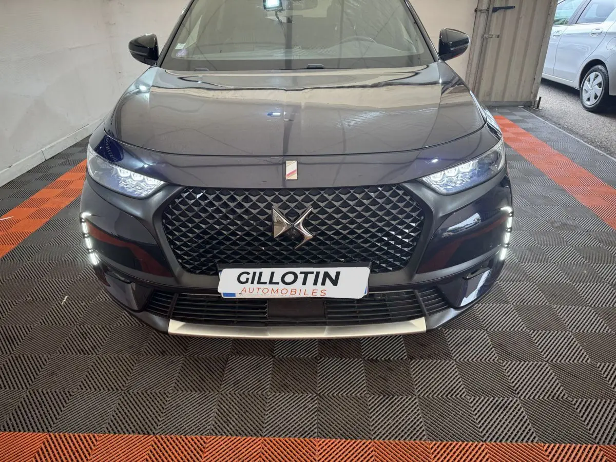 Vue frontale du DS7 Crossback E-TENSE bleu, mettant en valeur sa calandre distinctive et ses feux LED allumés.