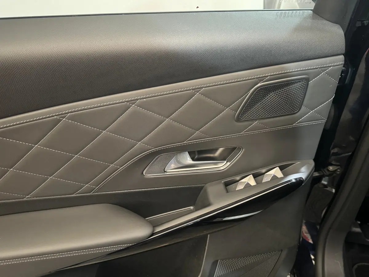 Gros plan sur la porte intérieure côté gauche du DS7 Crossback bleu, avec surpiqûres et commandes de vitres.