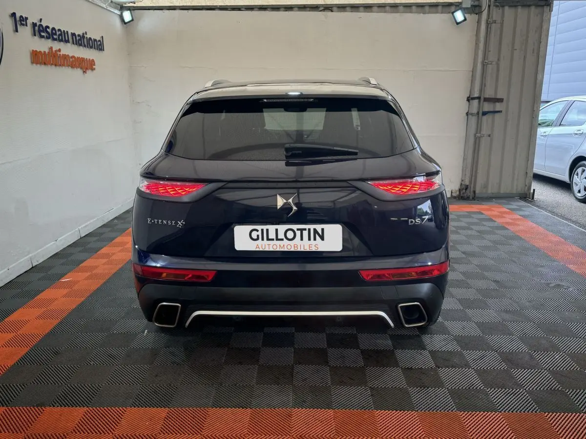Vue arrière du DS7 Crossback E-TENSE bleu avec feux LED allumés et double sortie d'échappement carrée.