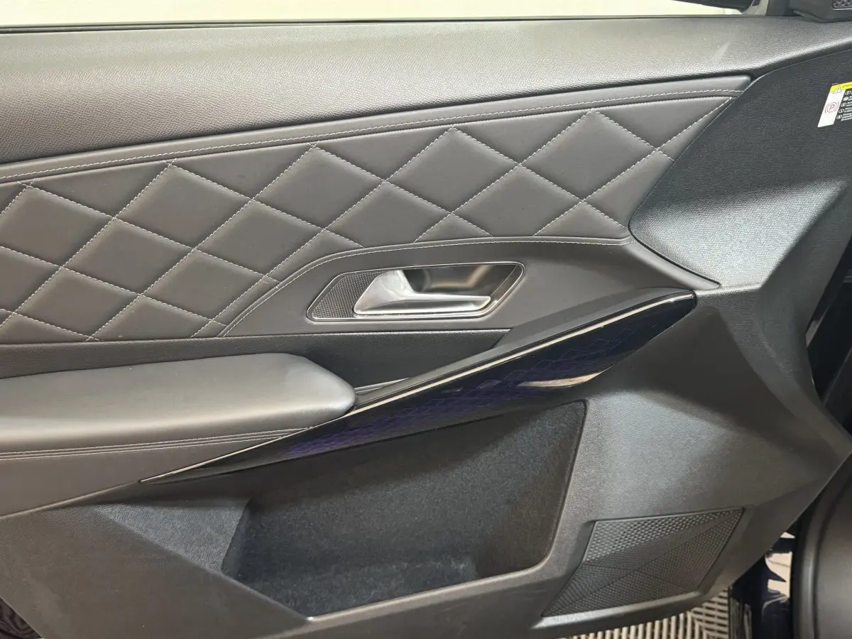 Gros plan sur la porte côté gauche du DS7 Crossback bleu, avec cuir matelassé et insert brillant à motifs géométriques.