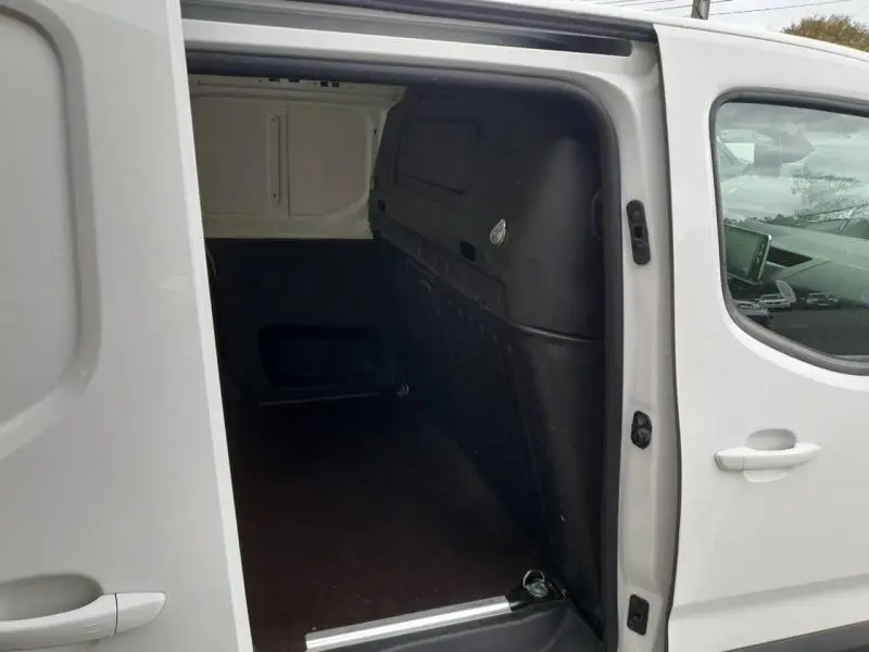 Vue côté droit du fourgon blanc Peugeot Partner 2019 avec porte latérale ouverte montrant l'espace de chargement vide.