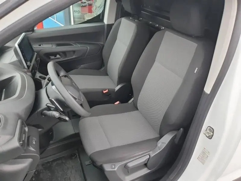 Vue intérieure côté conducteur du Peugeot Partner blanc, montrant les sièges gris et le tableau de bord moderne avec écran tactile.