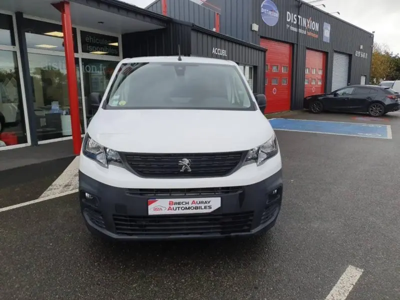 Vue frontale d'un Peugeot Partner blanc banquise stationné devant un garage avec logo Brech Auray Automobiles.