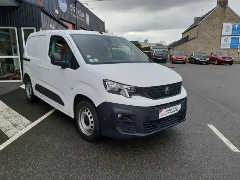 Peugeot Partner blanc vue 3/4 avant droit avec pare-chocs noir et jantes acier en extérieur gris.
