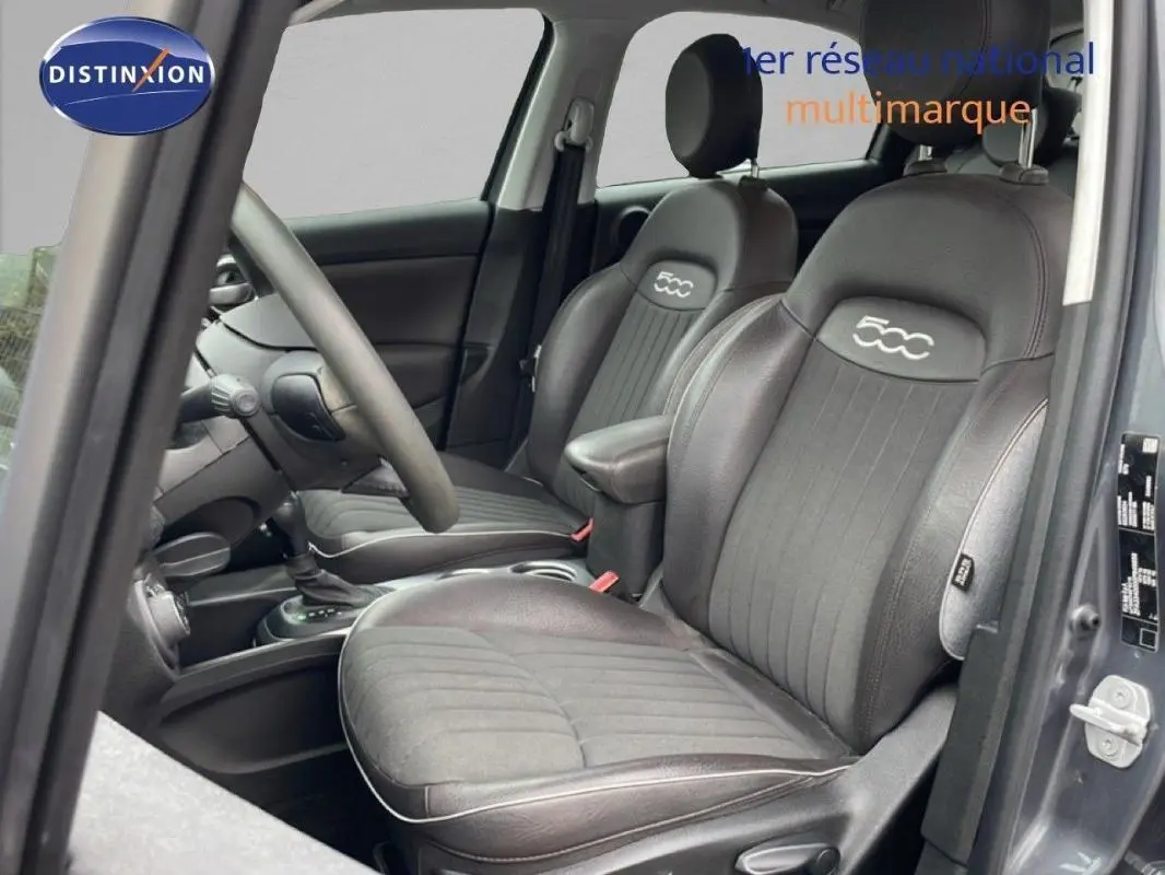 Vue intérieure côté conducteur du Fiat 500X gris foncé, sièges en cuir noir avec logo 500 brodé.