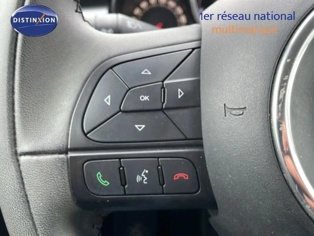 Gros plan sur les commandes au volant à gauche du Fiat 500X gris foncé MY18 avec boutons de gestion d'appels et menu.