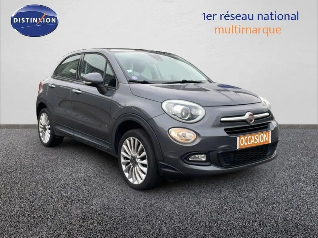Fiat 500X gris foncé vue 3/4 avant droit, avec jantes alliage 18 pouces et plaque occasion visible.