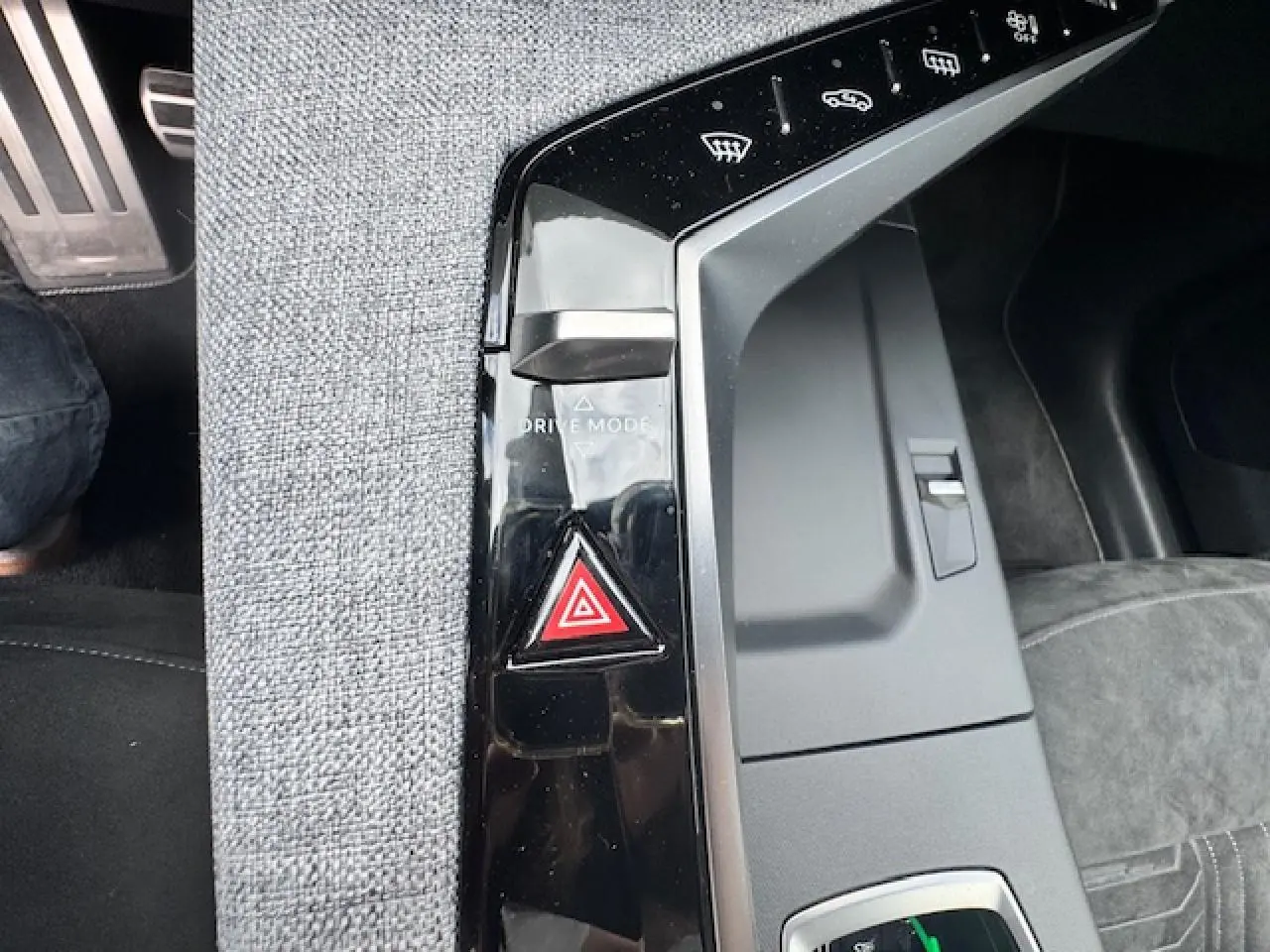 Détail de la console centrale noire brillante avec bouton de mode de conduite et alerte de danger dans un Peugeot 3008 gris Artense 2024.