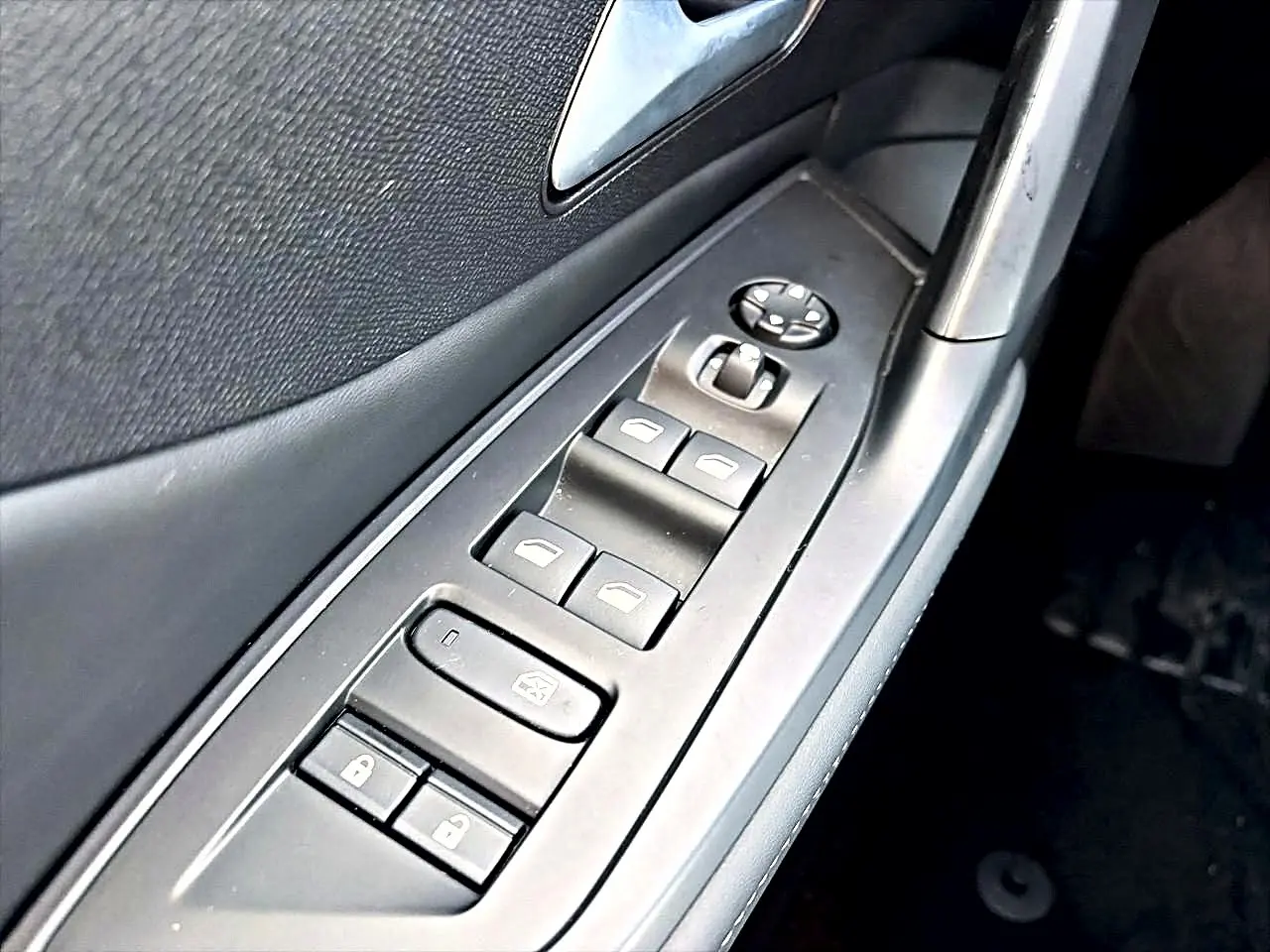 Gros plan sur les commandes des vitres et rétroviseurs côté conducteur d'une Peugeot 408 noire, intérieur sombre.
