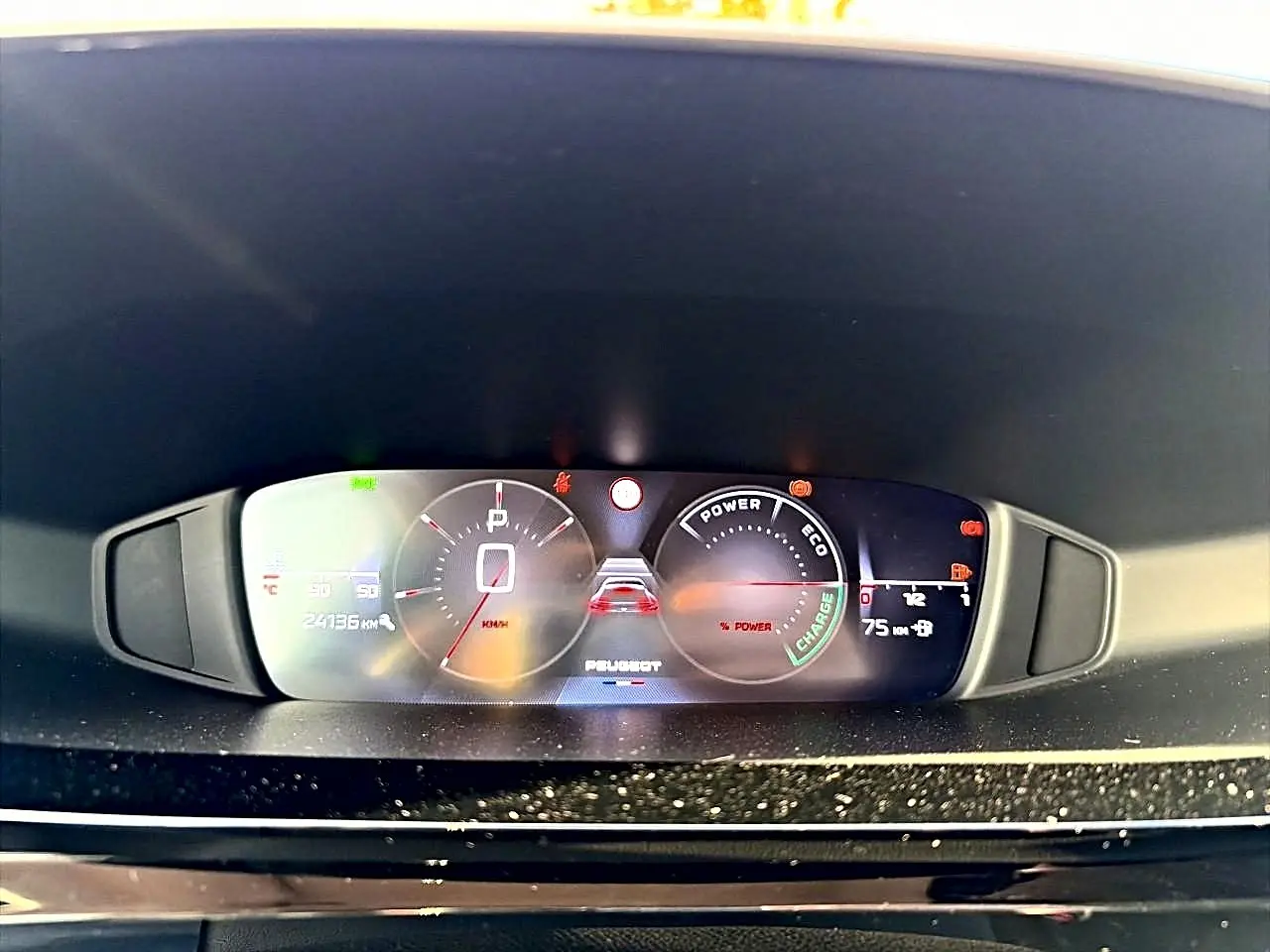 Vue rapprochée du tableau de bord numérique de la Peugeot 408 Hybrid 145 allure noir, affichant la vitesse et les indicateurs d'énergie.