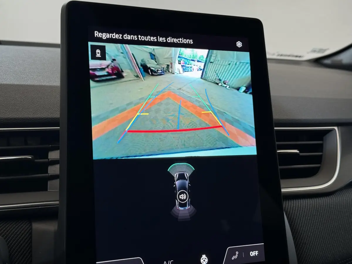 Écran tactile central du Renault Captur blanc 2025 montrant la caméra de recul avec lignes de guidage colorées.