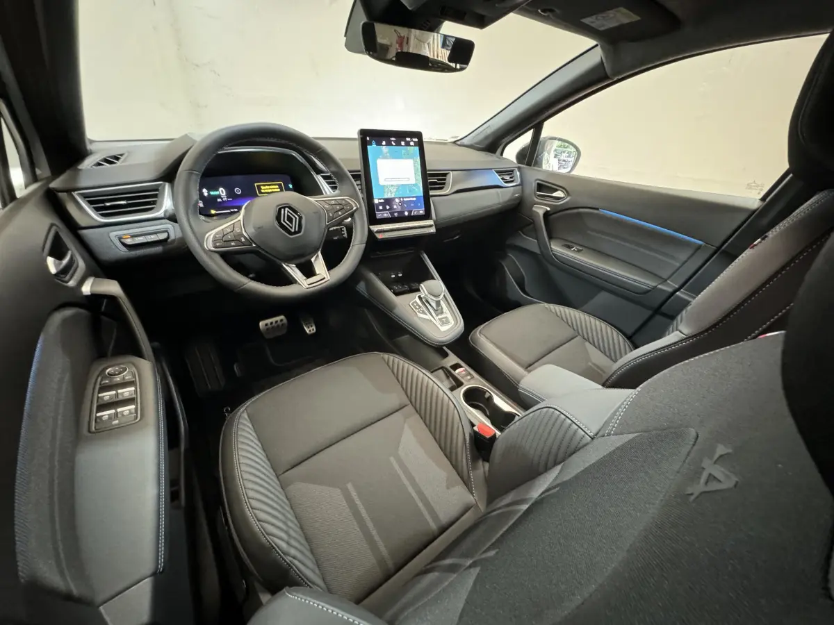 Vue intérieure avant droite du Renault Captur esprit Alpine E-Tech 2025, avec tableau de bord numérique et écran tactile vertical.