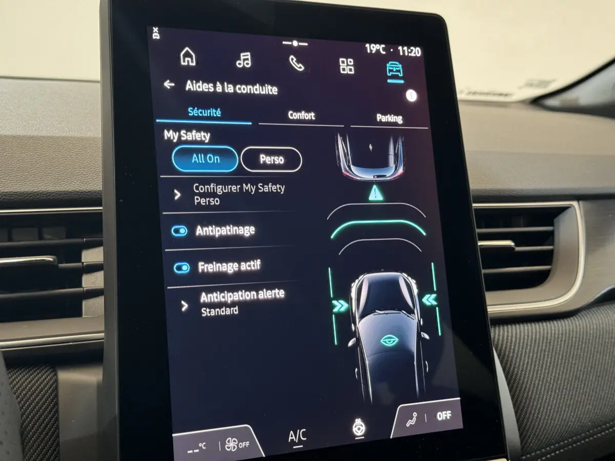 Écran tactile central du tableau de bord du Renault Captur blanc 2025 montrant les aides à la conduite.