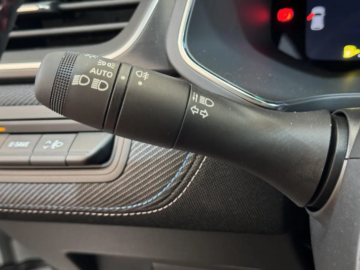 Gros plan sur la commande des phares et clignotants du tableau de bord intérieur du Renault Captur blanc esprit Alpine E-Tech.