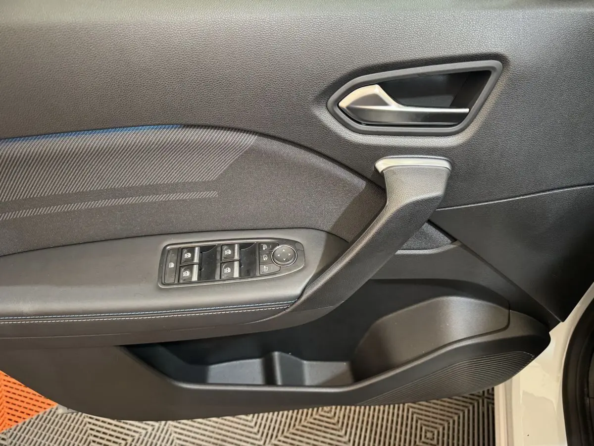 Gros plan sur la porte côté gauche du Renault Captur blanc 2025, avec commandes électriques et poignée intégrée.