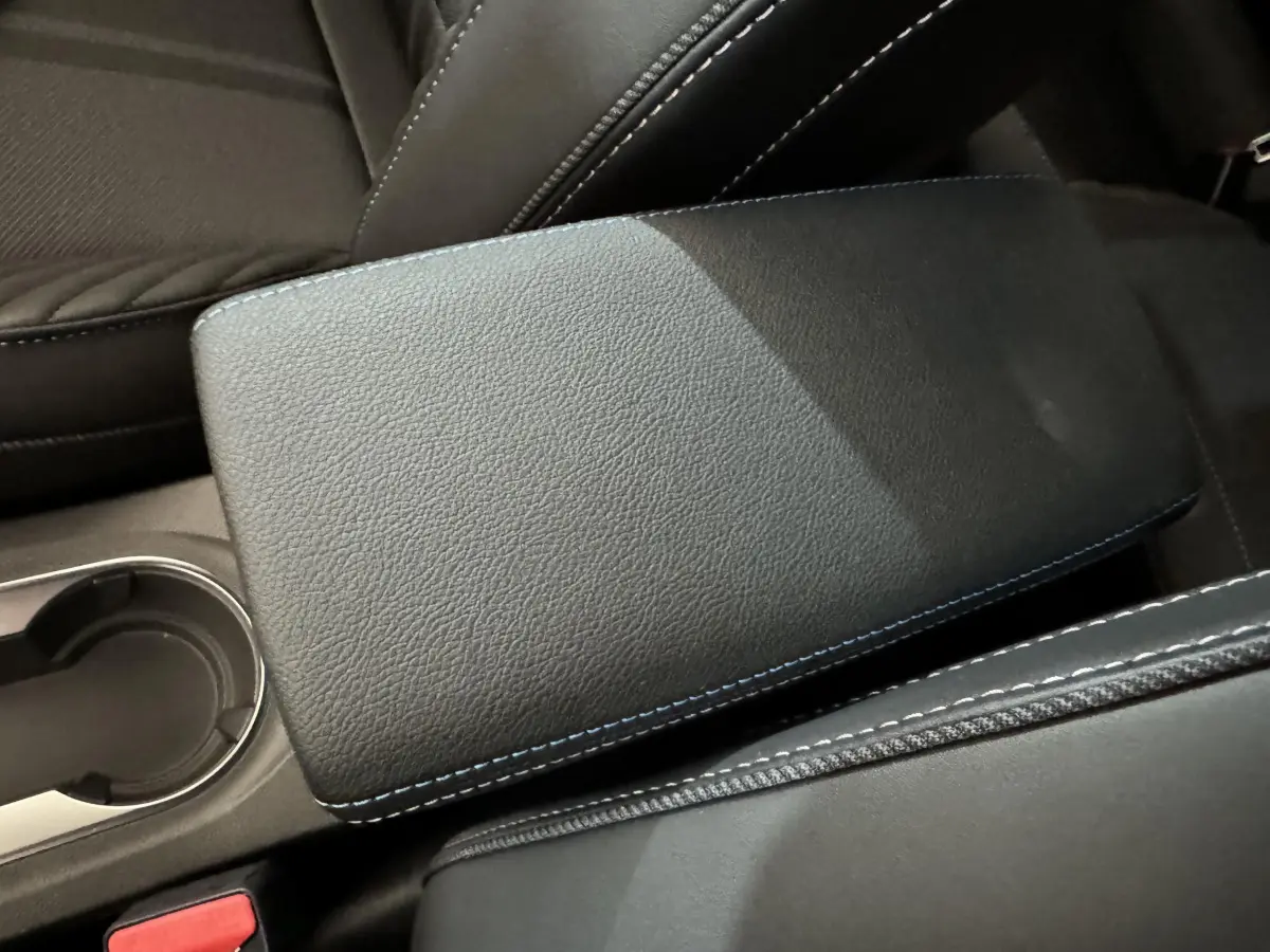 Accoudoir central noir avec surpiqûres bleues, vue rapprochée de l'intérieur du Renault Captur blanc esprit Alpine E-Tech.