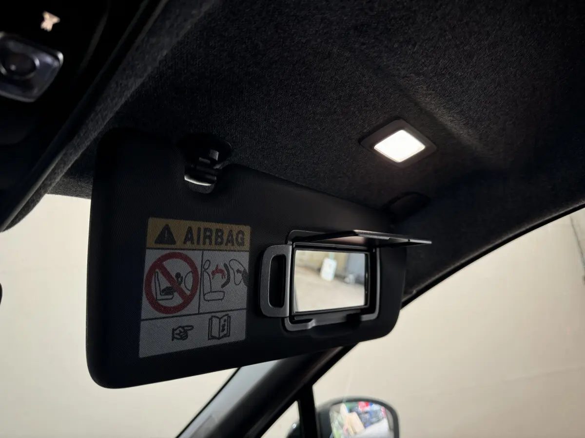 Détail du pare-soleil côté conducteur avec miroir intégré et éclairage intérieur allumé d'un Renault Captur blanc 2025.