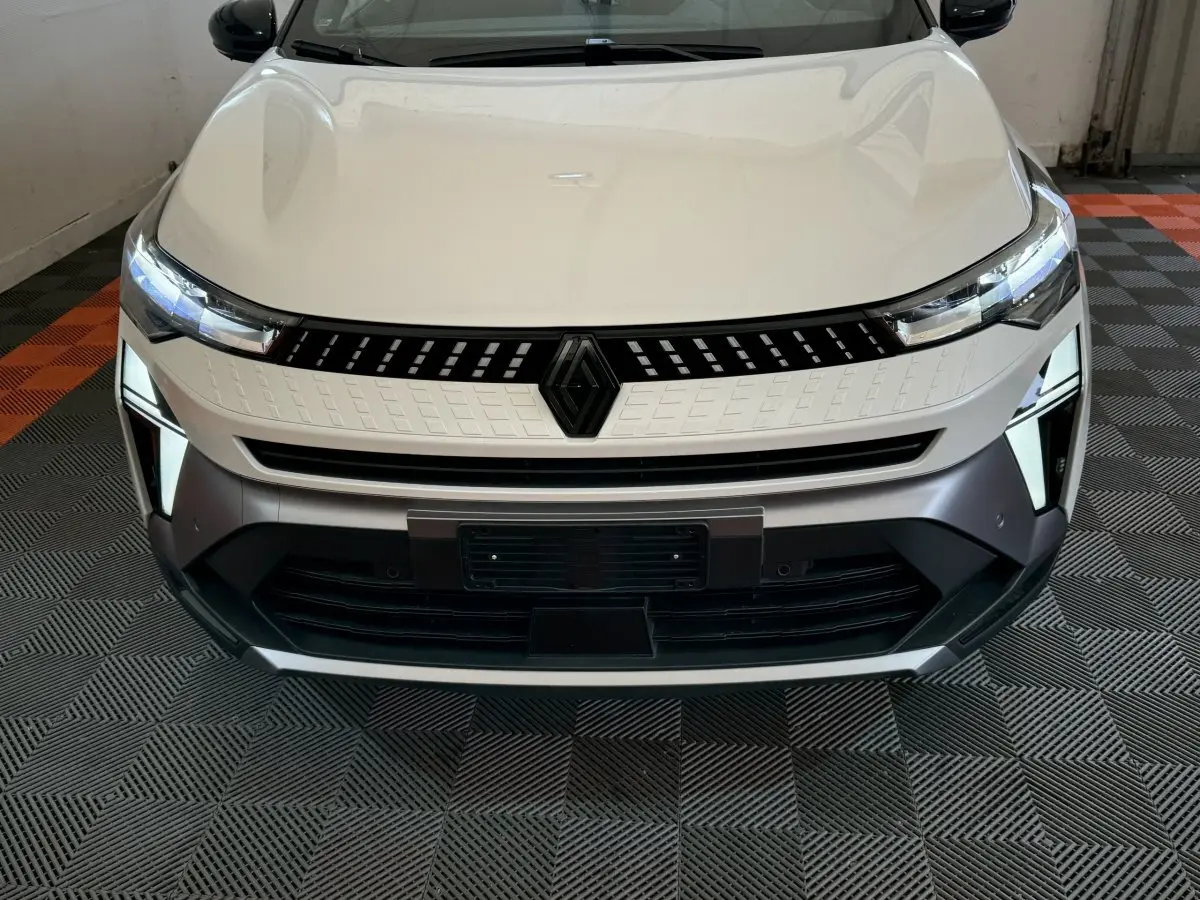 Vue frontale rapprochée du Renault Captur blanc esprit Alpine E-Tech 2025 avec calandre et phares LED allumés.