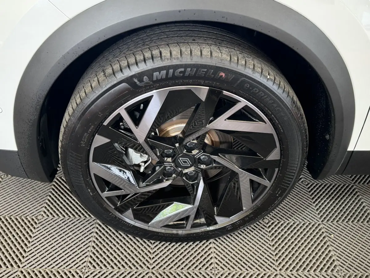 Gros plan sur la roue avant droite du Renault Captur blanc 2025 avec jante alliage noir et gris au design géométrique.