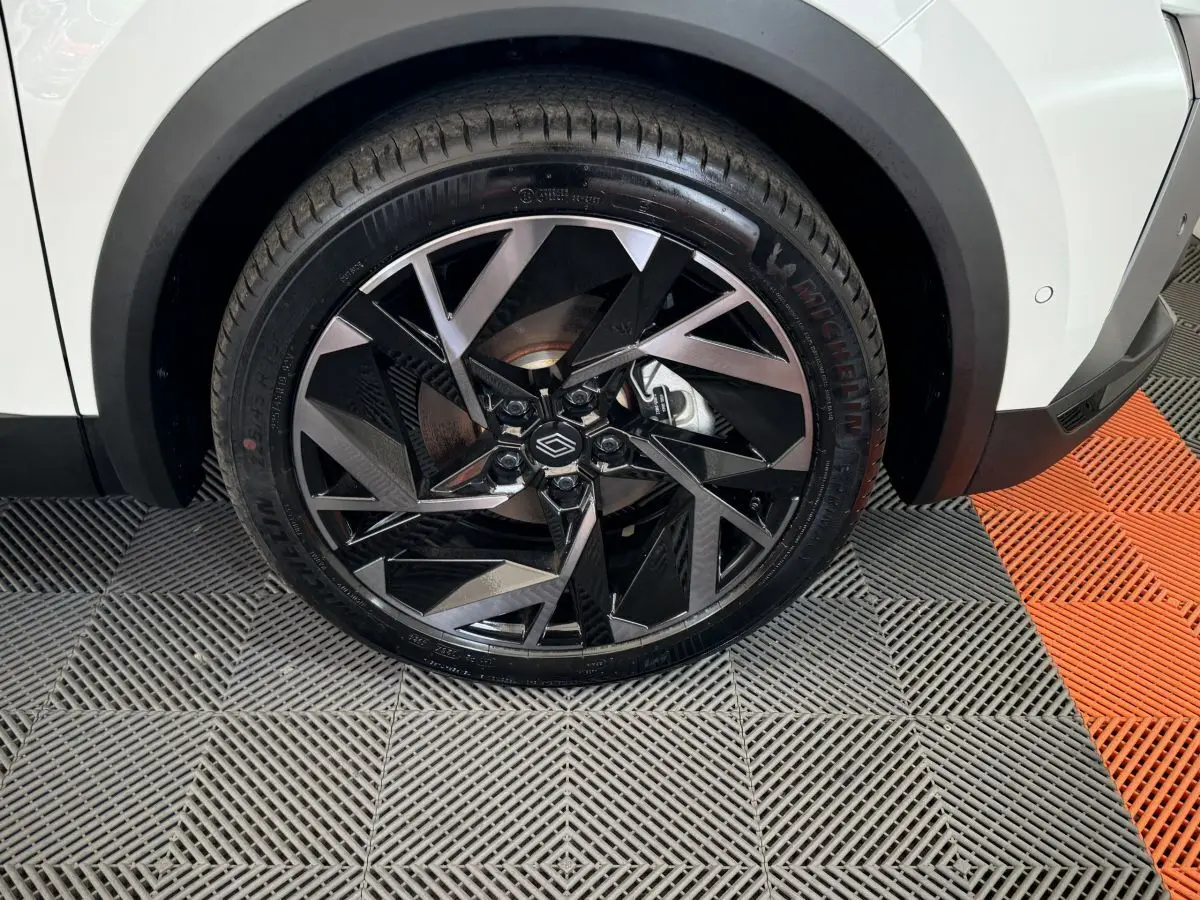 Gros plan sur la roue avant droite du Renault Captur blanc esprit Alpine E-Tech, jante noire et argent au design géométrique.