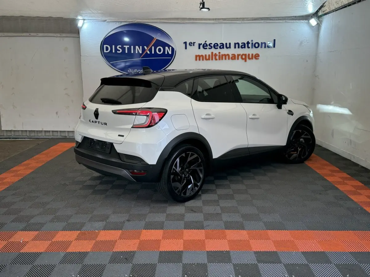 Vue 3/4 arrière droite du Renault Captur blanc esprit Alpine E-Tech avec toit noir et jantes noires en showroom.
