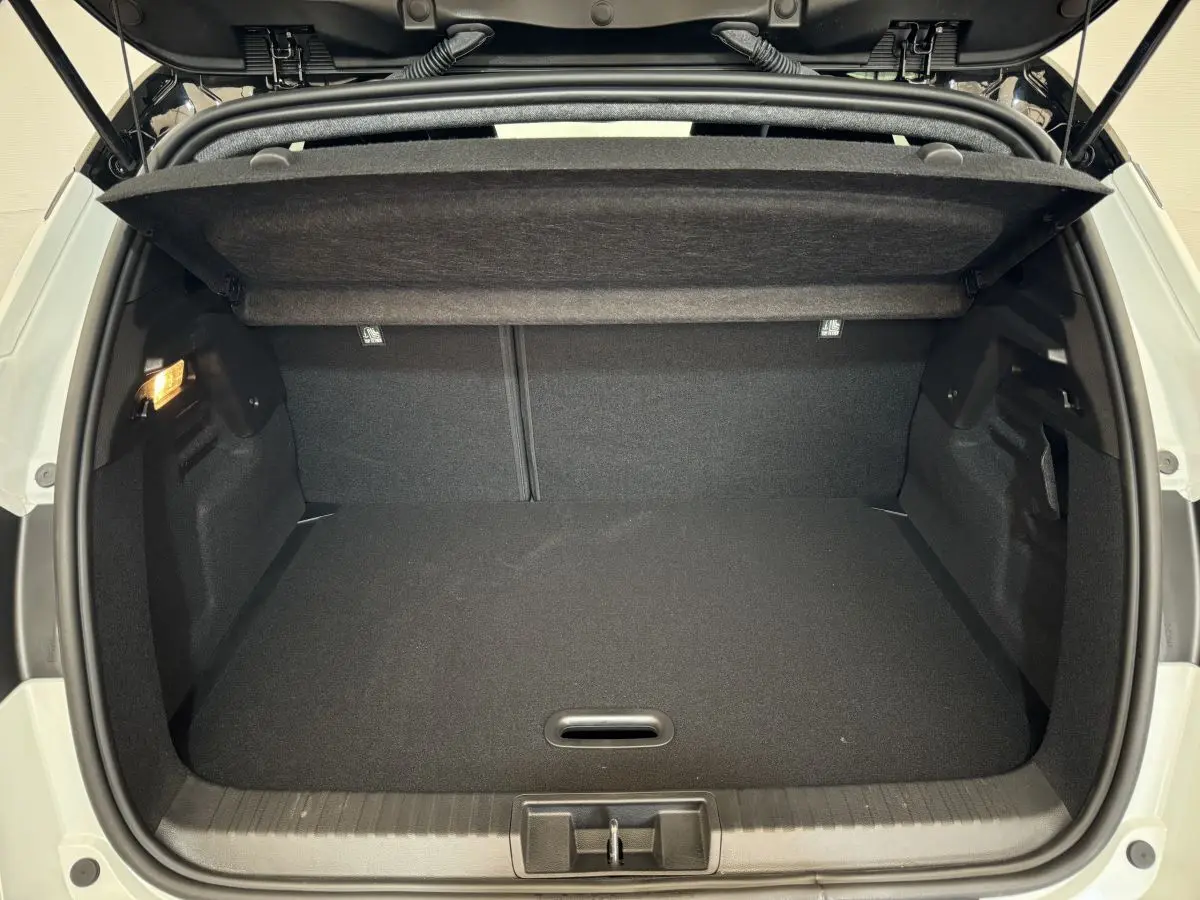 Coffre ouvert vu de l'arrière du Renault Captur blanc esprit Alpine E-Tech 2025, intérieur noir et éclairage latéral.