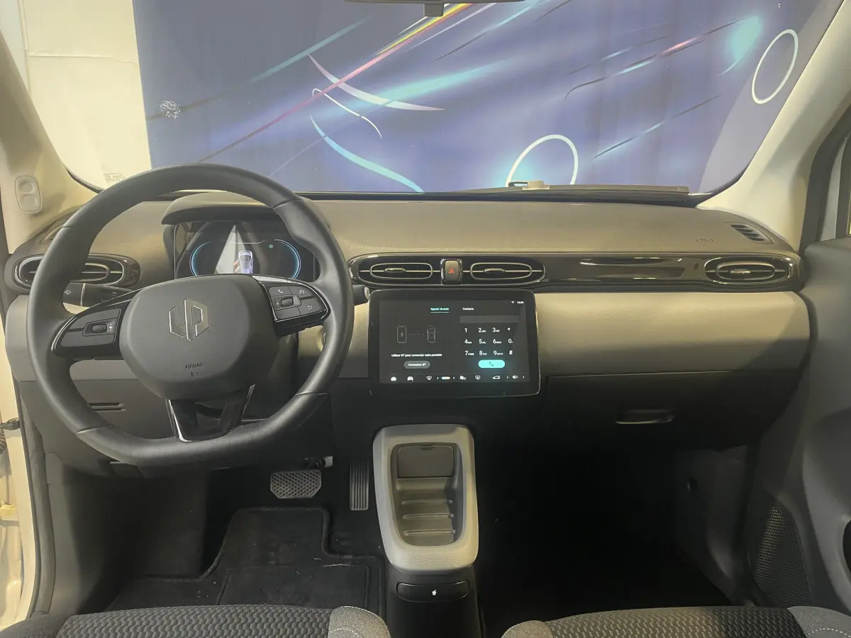 Vue intérieure frontale du tableau de bord du Leapmotor T03 Luxury blanc avec volant cuir multifonctions et écran tactile central.