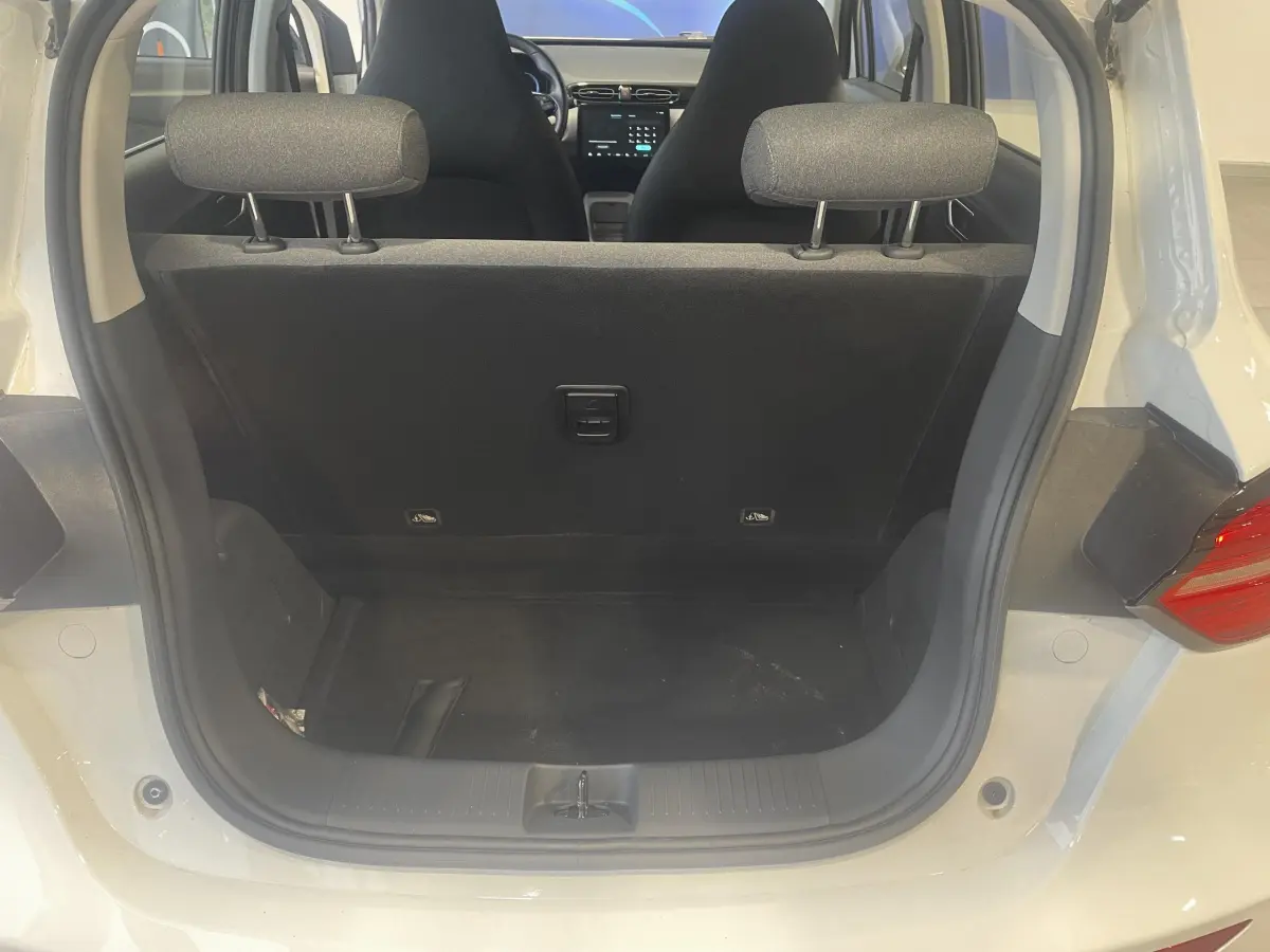 Vue arrière du coffre ouvert d'une LEAPMOTOR T03 Luxury blanche, montrant l'intérieur noir et les sièges avant.