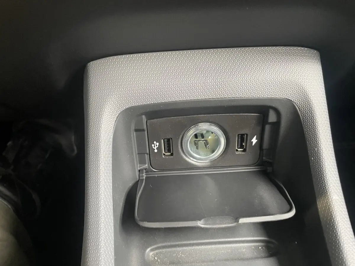 Gros plan sur la prise 12V et ports USB dans la console centrale du Leapmotor T03 Luxury blanc, intérieur sombre.