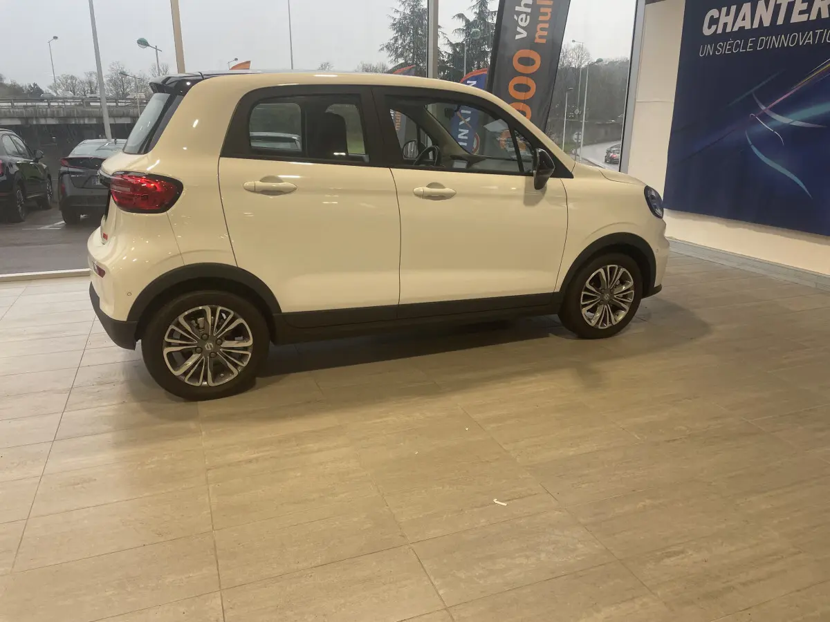 Vue de profil côté gauche d'une LEAPMOTOR T03 Luxury blanche, compacte et électrique, en intérieur showroom.