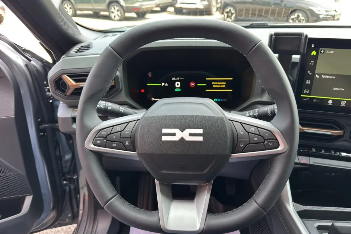 Vue intérieure centrée sur le volant cuir du Dacia Bigster gris schiste avec tableau de bord digital et écran tactile.