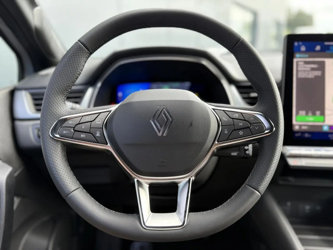 Volant multifonction en cuir Renault vu de face avec tableau de bord numérique et écran tactile à droite.