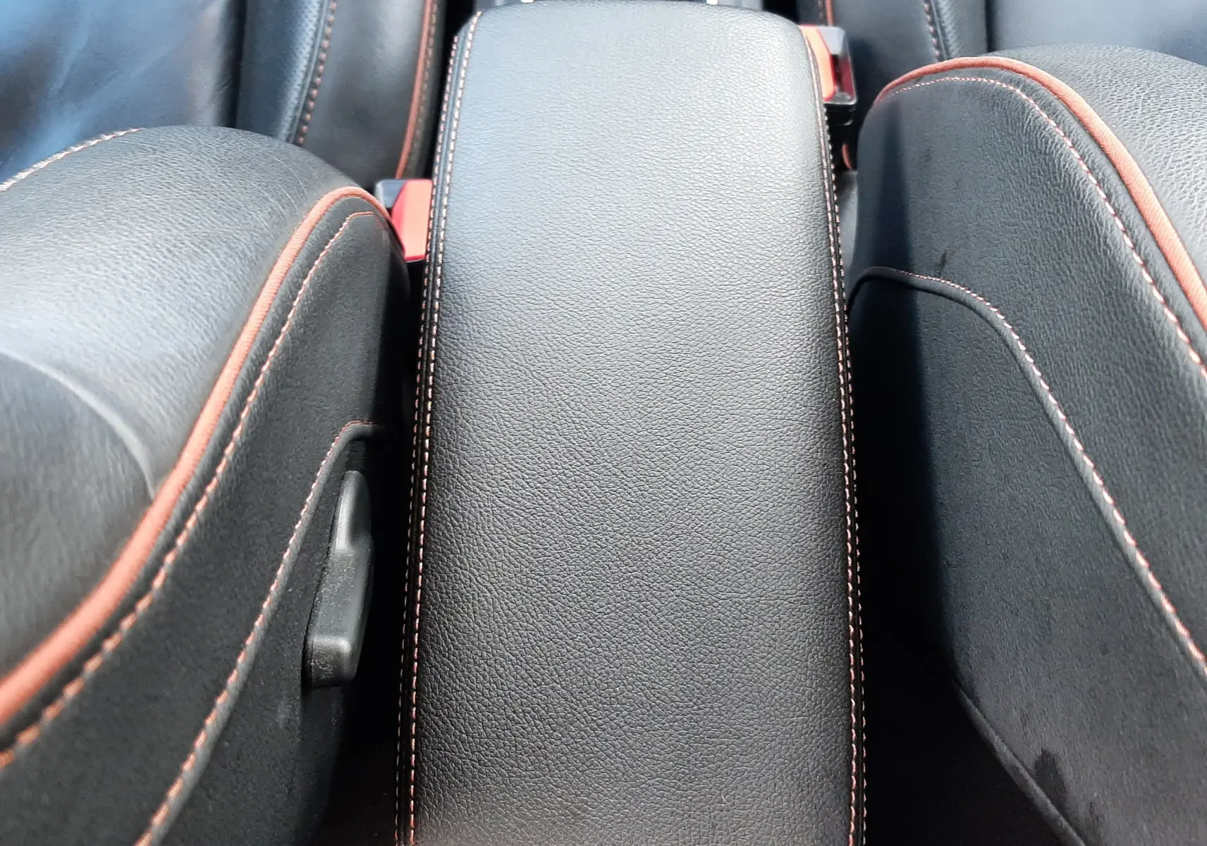 Accoudoir central en cuir noir avec surpiqûres orange entre les sièges avant du Renault Captur blanc toit noir 2020.