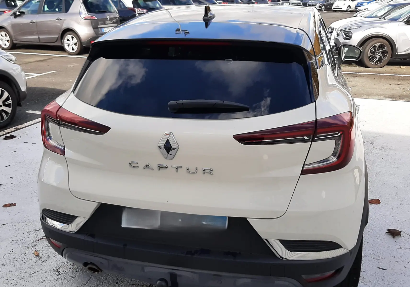 Vue arrière d'un Renault Captur blanc avec toit noir, montrant les feux LED et l'attelage de remorque.