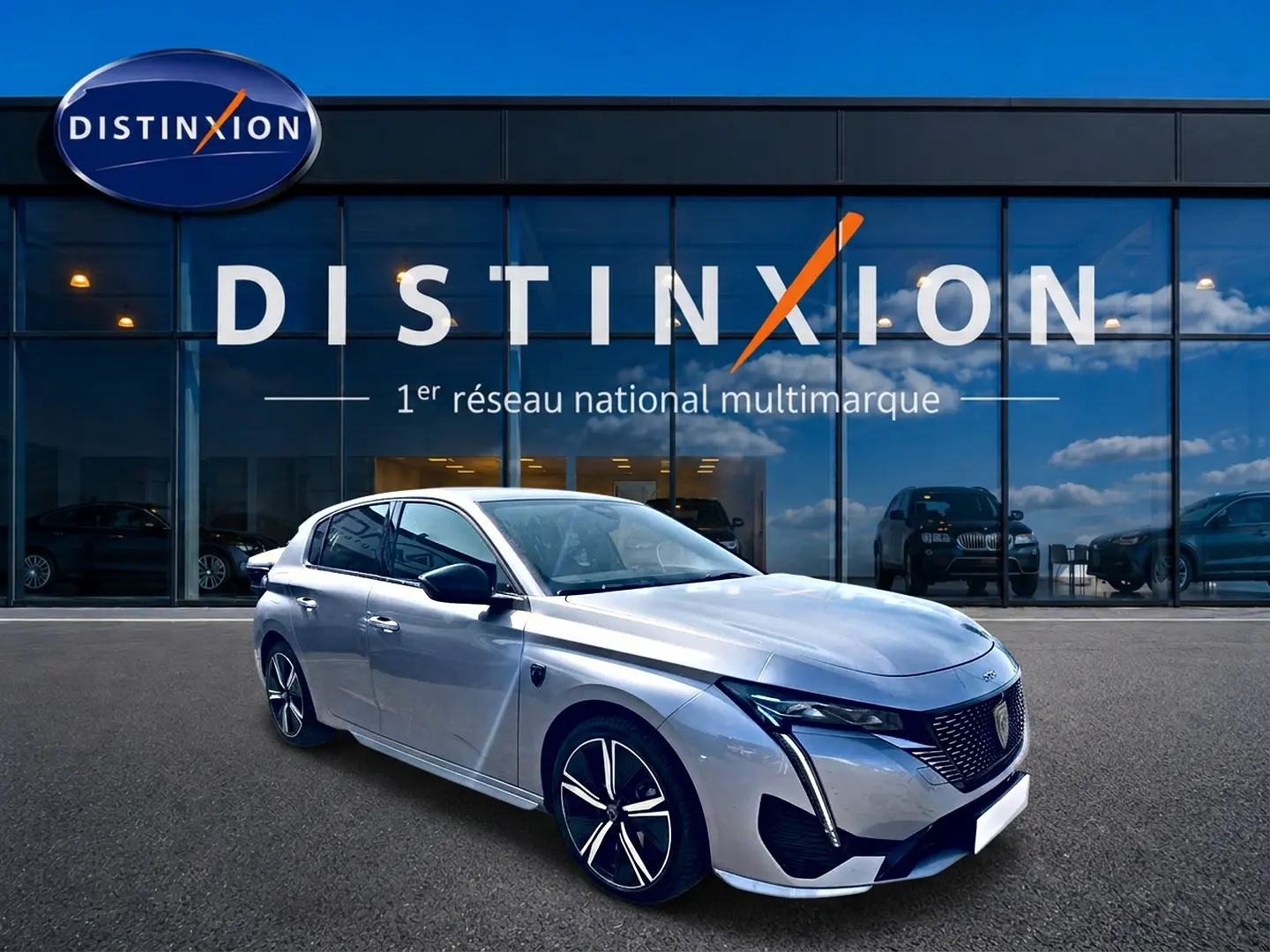 Peugeot 308 gris vue 3/4 avant droit, avec calandre distinctive et jantes alliage modernes devant showroom Distinxion.
