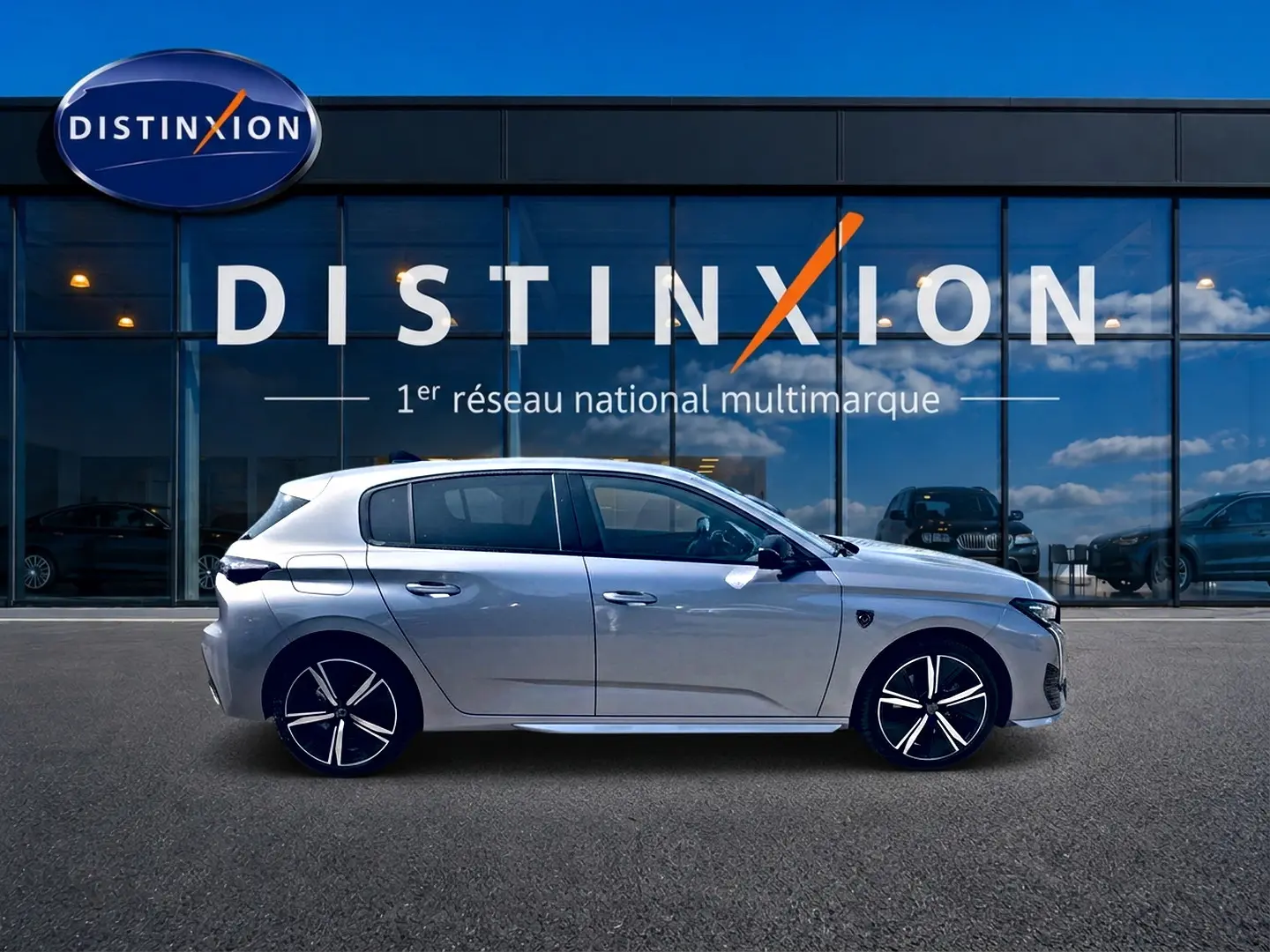Peugeot 308 gris vue de profil côté gauche, avec jantes alu distinctives, devant une vitrine Distinxion.
