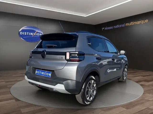 Vue 3/4 arrière droite d'une Citroën C3 gris foncé 2025 avec spoiler de coffre et feux arrière LED distinctifs.
