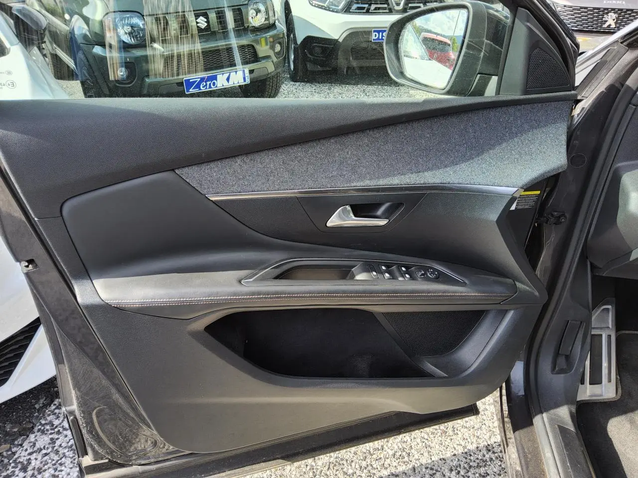 Gros plan sur la porte avant gauche intérieure du Peugeot 3008 gris métallisé, avec commandes électriques et garniture tissu et cuir.