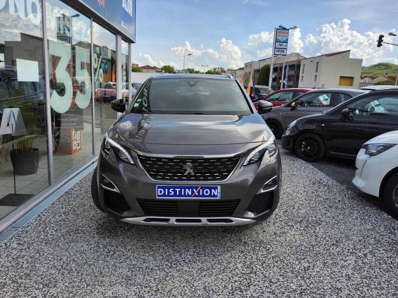Peugeot 3008 gris métallisé vue de face, avec calandre chromée et plaques Distinxion visible.
