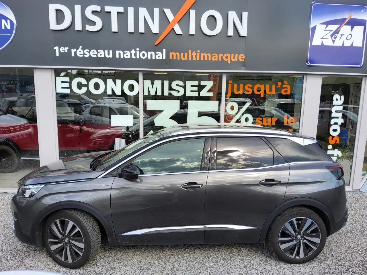 Peugeot 3008 GT Line gris métallisé vue de profil côté gauche devant une vitrine avec enseigne Distinxion.