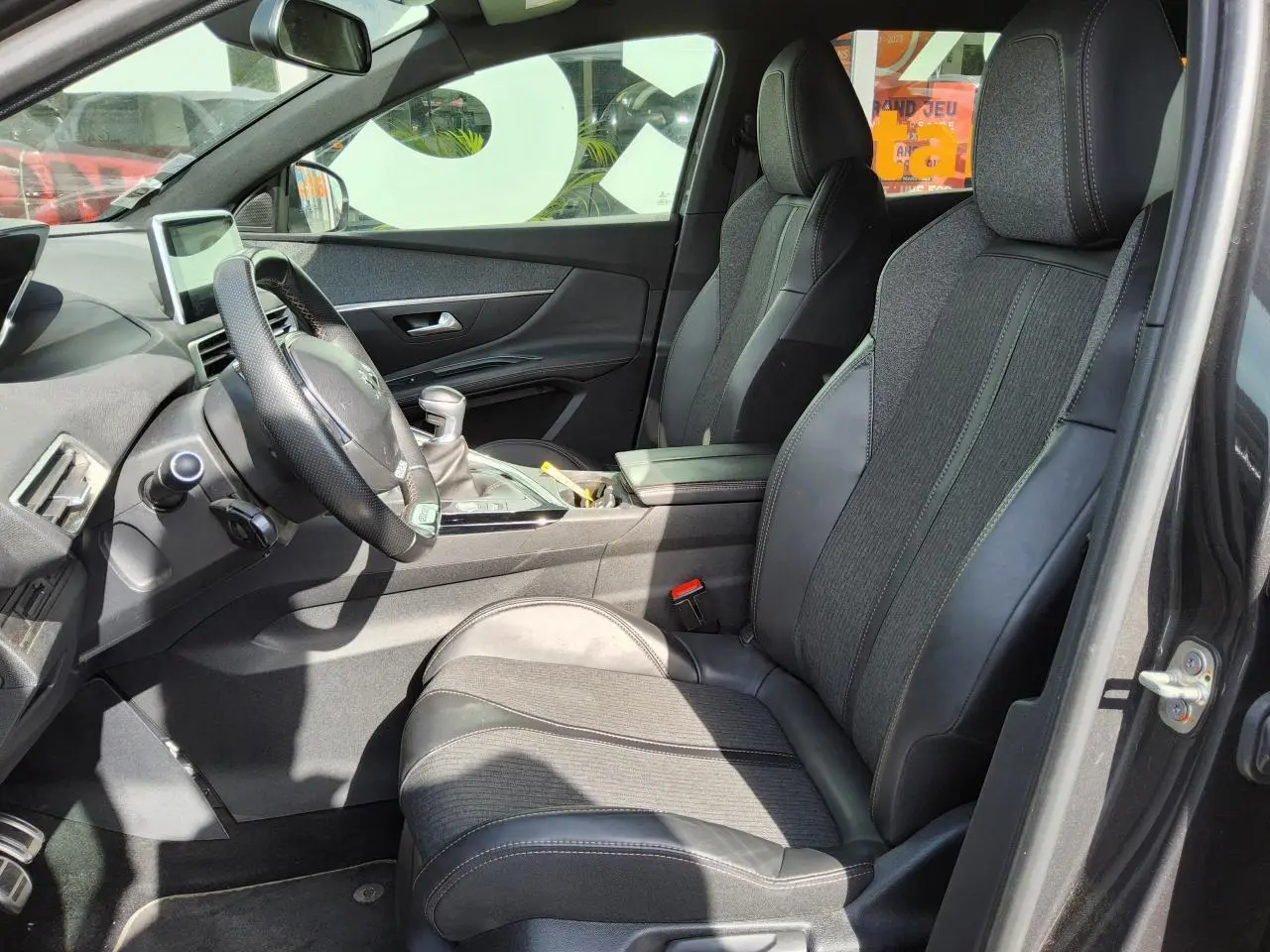 Vue intérieure côté conducteur du Peugeot 3008 GT Line 2017, sièges TEP et tissu noirs avec volant cuir perforé.